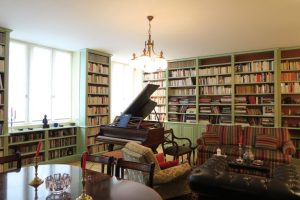 DECOR PEINT : dans un appartement parisien, filets dorés et clairs sur les moulures d’une bibliothèque verte.