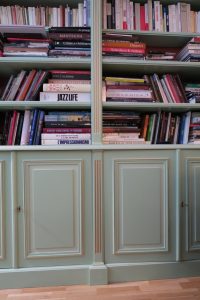 DECOR PEINT : dans un appartement parisien, filets dorés et clairs sur les moulures d’une bibliothèque verte. Détail.