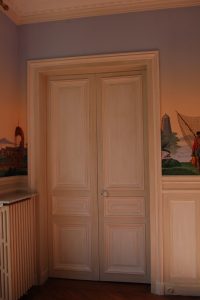 DECOR CLASSIQUE : Sur les boiseries, décor classique composé de patines pastillées de ton gris, avec moulures et filets sur les panneaux de ton blanc cassé.