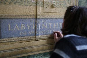 TROMPE L’ŒIL : détail du plan du labyrinthe de Versailles, avec fausses moulures ornementées, lettres peintes et décor végétal - décor en cours