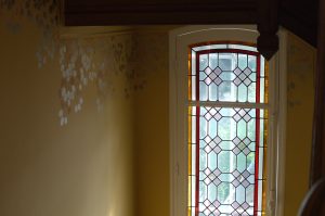 RESTITUTION : sur les parties hautes et basses des murs des escaliers et paliers d’un hôtel particulier de style Art Nouveau d’Ile de France, décor de frise végétale de tons rosé, corail, or et argent, avec un jeu de brillance sur mat.