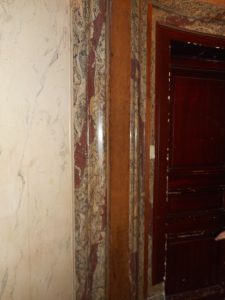 AVANT RESTAURATION : état des faux bois imitant l’acajou sur la porte palière et des stucs marbres avant la rénovation des gaines électriques (ici en ton bois sur le stuc marbre)