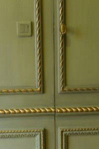 DECOR PEINT : Dans un petit salon d’un appartement parisien, réalisation d’un décor néoclassique de patines de ton vert sur les murs et de ton beige sur la corniche, avec filets de dorure sur les moulures ornementées. (Détail de panneaux))