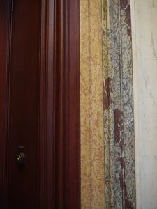 RESTAURATION : restitution des stucs marbres suite à la rénovation des gaines électriques et restitution de l’imitation acajou sur les portes palières (détail)