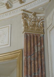 Faux marbres et dorure : Dans une chambre d’un appartement parisien en décor de style néoclassique XVIIIe siècle, avec patntes et filets dorés, faux marbres et dorures sur les pilastres et la cheminée - détail