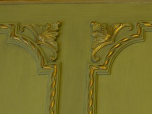 DECOR PEINT : Dans un petit salon d’un appartement parisien, réalisation d’un décor néoclassique de patines de ton vert sur les murs et de ton beige sur la corniche, avec filets de dorure sur les moulures ornementées. (Détail de motifs d'angles)