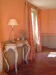 DÉCOR PEINT : Dans le salon d'un mas provençal, décor de facture modeste, en composition de 2 tons de patines; soubassement en patine gris vert, avec fausses moulures et motif de frise.