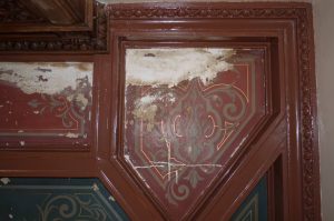 RESTAURATION : Dans les caissons au plafond d'une salle à manger de style néogothique, restauration des décors de motifs et filets taupe et dorés, sur fonds verts ou rouges. Détail du plafond avant restauration.