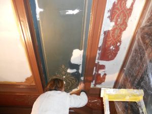 RESTAURATION : Dans les caissons au plafond d'une salle à manger de style néogothique, restauration des décors de motifs et filets taupe et dorés, sur fonds verts ou rouges. Détail du plafond pendant restauration.
