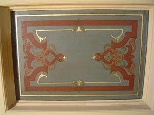 RESTAURATION : Dans une salle à manger de style néogothique d’un immeuble du XIXe siècle de style éclectique, restauration des décors des caissons du plafond très endommagé; décors de motifs et filets rouges et dorés, sur fonds verts ou rouges. Détail.