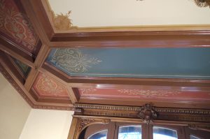 RESTAURATION : Dans les caissons au plafond d'une salle à manger de style néogothique, restauration des décors de motifs et filets taupe et dorés, sur fonds verts ou rouges. Détail.