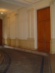Portes en faux bois : sur les murs du vestibule d'un immeuble Haussmannien, réalisation de filage de pierre, de faux marbre Blanc Veiné sur les pilastres d'Henriette et Comblanchien sur les plinthes et soubassements. Restauration de toutes les portes en Imitation Chêne.