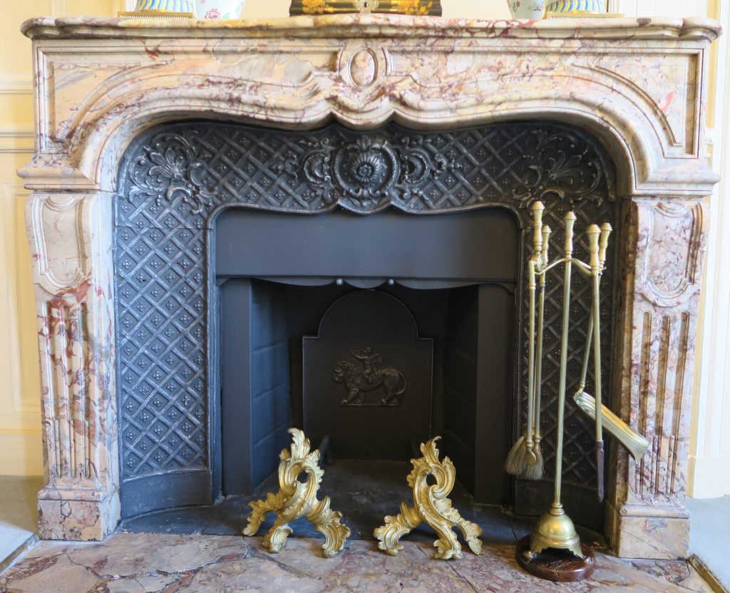 DECOR PEINT : dans un salon décor classique, le manteau de cheminée et la plaque sont imitation fonte, avec rehauts argentés sans ostentation.