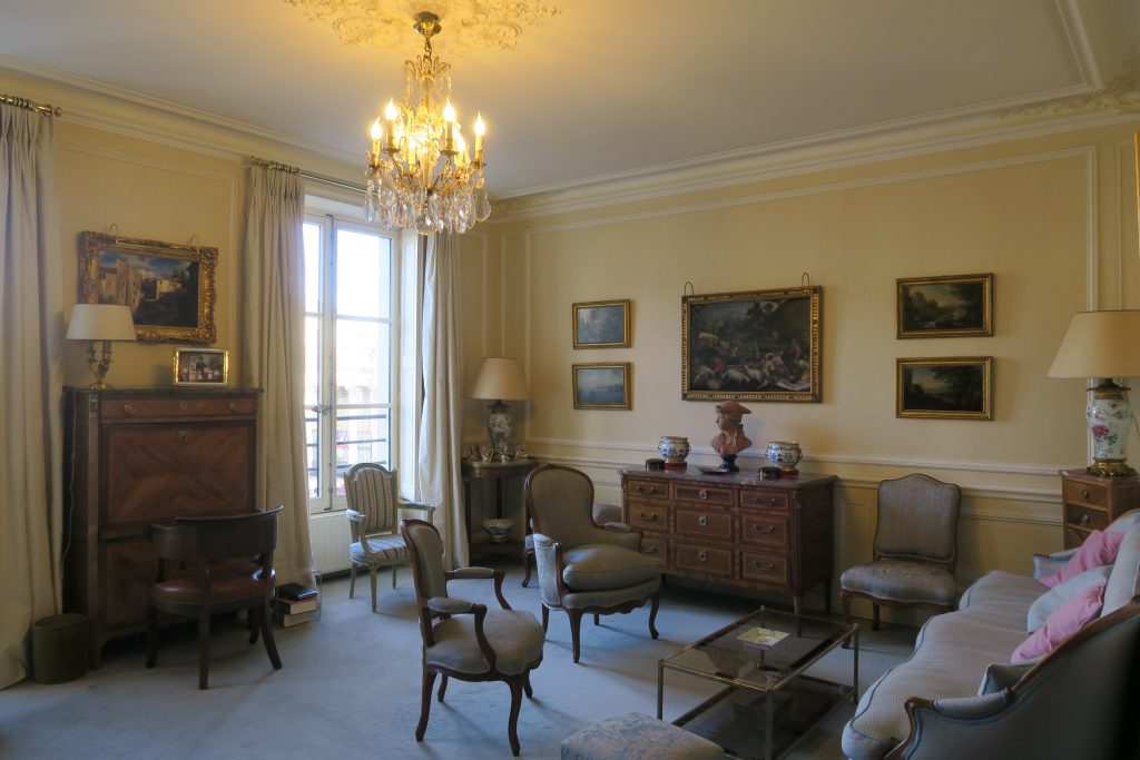 DECOR PEINT : dans un salon décor classique composé de patine spaltée ton paille, avec moulures blanc cassé et rehauts bleus