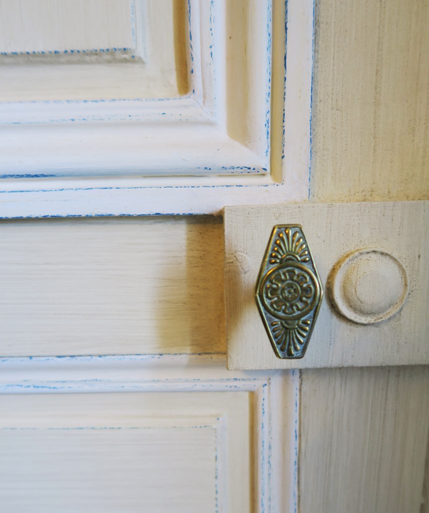 DECOR PEINT : dans un salon décor classique composé de patine spaltée ton paille, avec moulures blanc cassé et rehauts bleus; Détail.