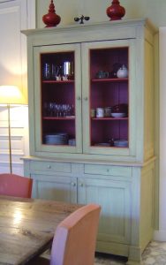 MEUBLE PEINT : décor de vaisselier provincial de salle à manger, faisant contraster la simplicité de la patine vert amande à l'extérieur et et celle, rouge framboise à l'intérieur, afin de mettre en valeur les jolies vaisselles.