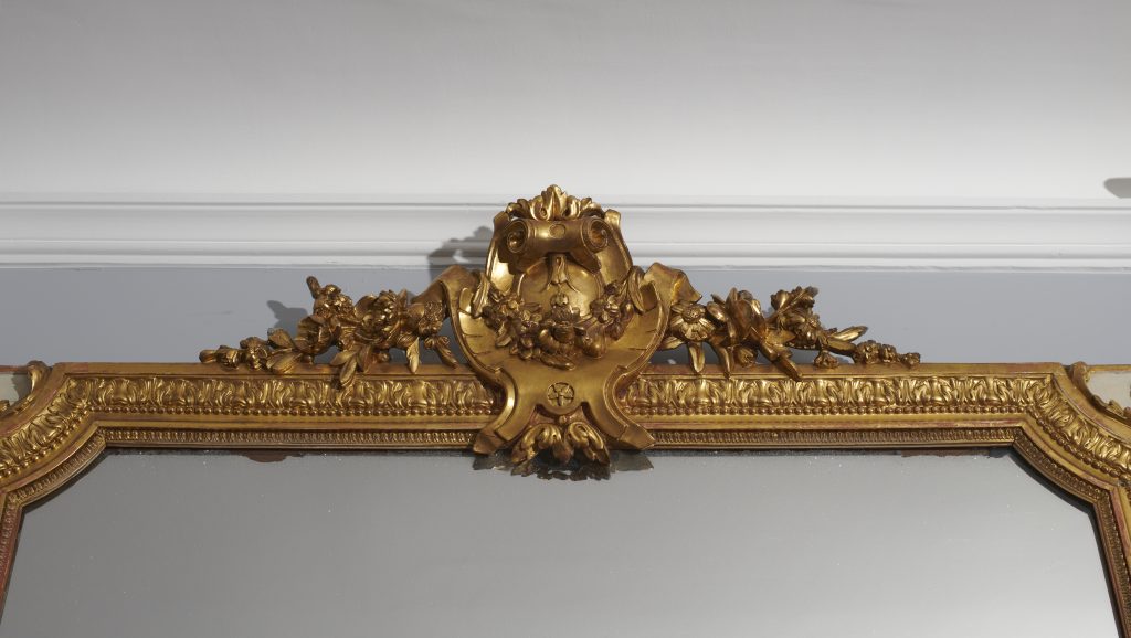 DORURE A LA FEUILLE : Sur le cadre très ouvragé du miroir de cheminée du salon d'un appartement parisien, restauration du cadre doré à la feuille, poli à l'agate.
