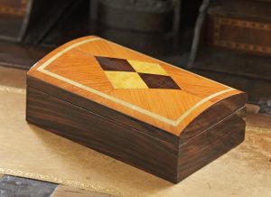 Sur une boite à gâteaux, imitation de marqueterie de bois de rose, d’érable et d’ébène de Macassar.