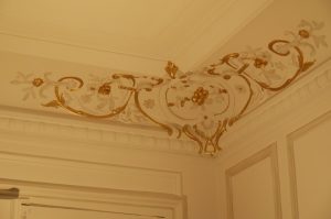 DECOR PEINT : réalisation, selon la demande, de décors de rehauts gris et dorés sur certains des beaux motifs d'angle des corniches au plafond d'un appartement Haussmannien (détail)
