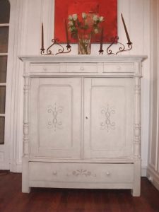 MEUBLE PEINT : Sur un buffet, composition douce de patine de tons gris et motifs.