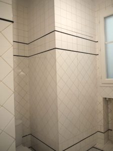 TROMPE L’ŒIL : Sur le placard en médium d'une salle de bain d’un appartement parisien, imitation des tons et motifs des carrelages contigus.